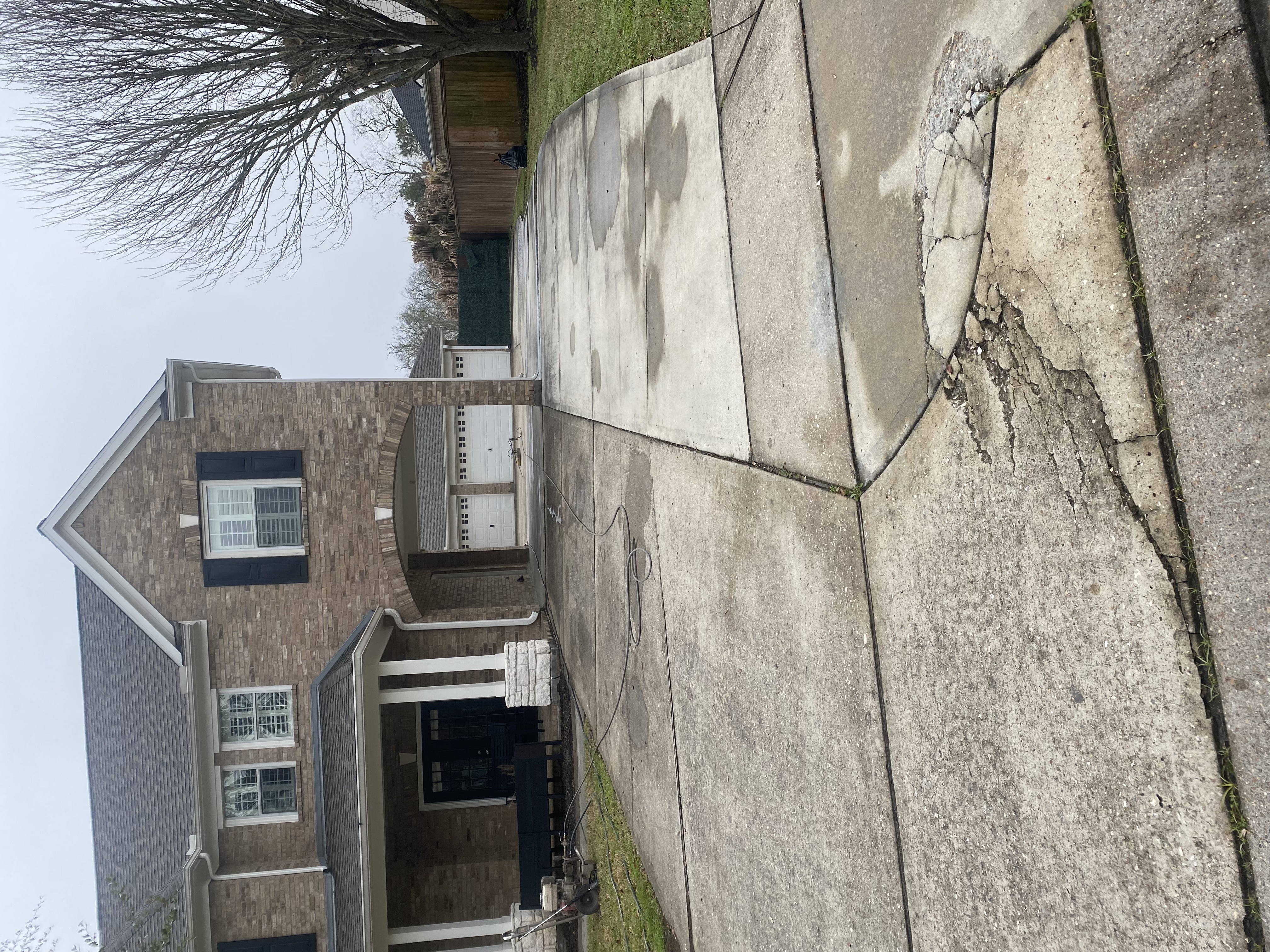Stained brick home driveway before
